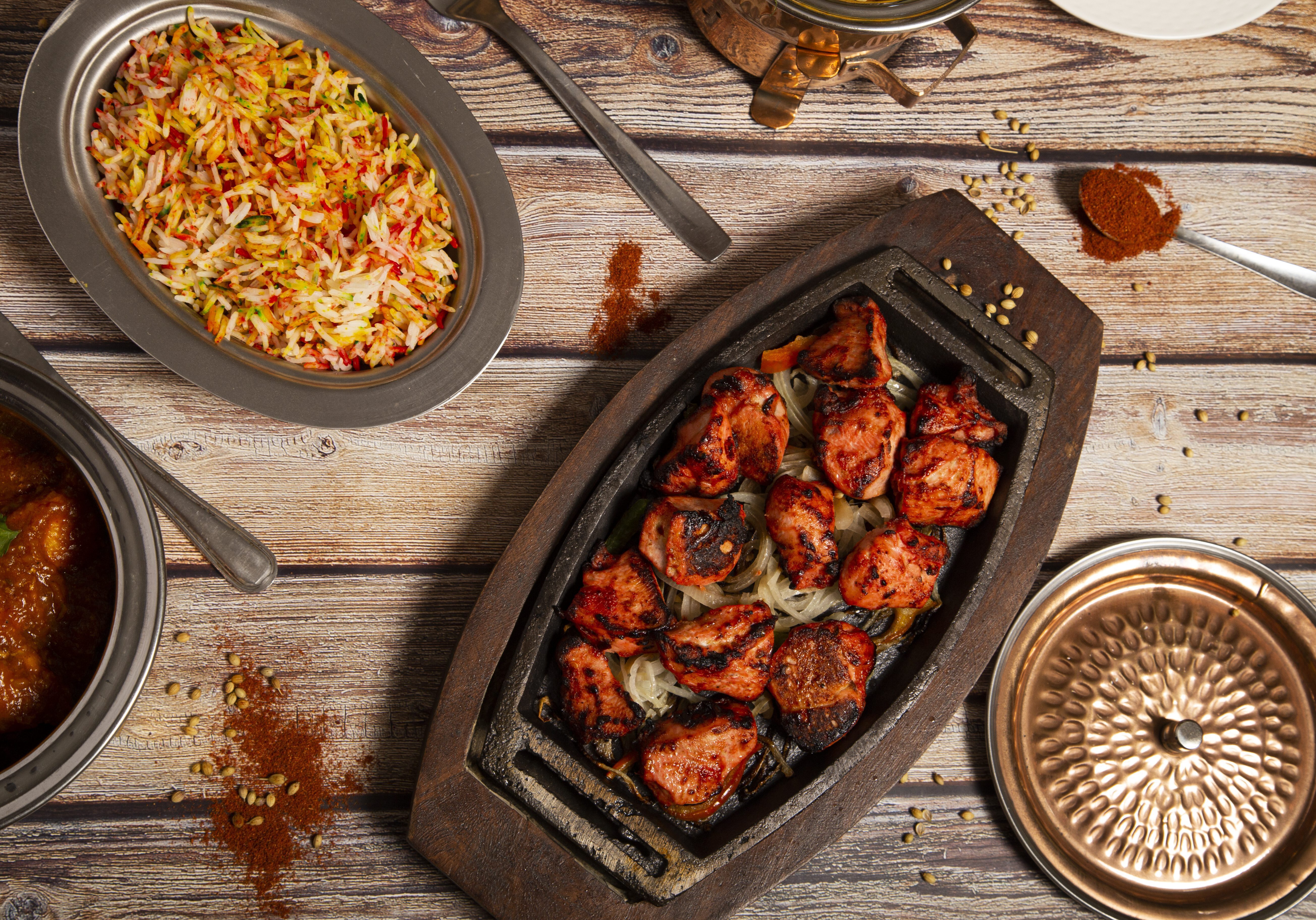 Variety of Indian curry food with tandoori chicken and basmati rice.