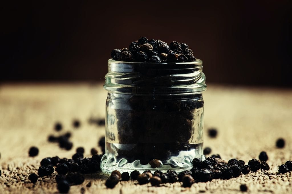 Pea of black pepper in a glass jar