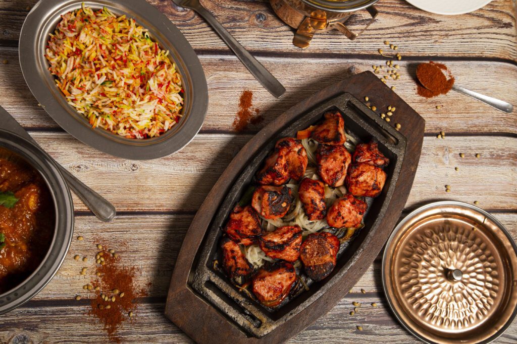 Variety of Indian curry food with tandoori chicken and basmati rice.